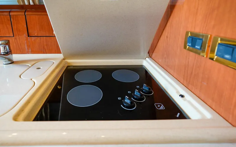  Yacht Photos Pics Stovetop in 2000 Sea Ray 510 Sundancer yacht kitchen, featuring four burners and wooden cabinetry.