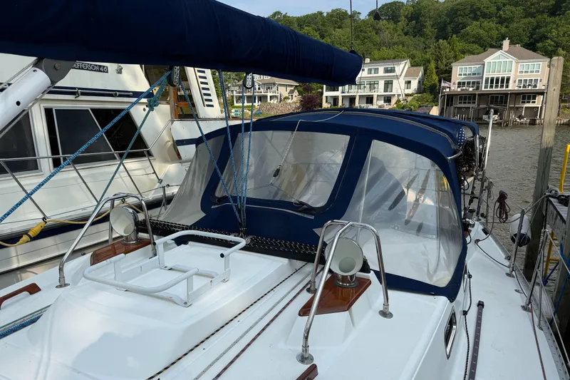 Nino Yacht Photos Pics Sailboat Tartan 4100 (2007) docked near waterfront homes, featuring blue canopy and rigging.