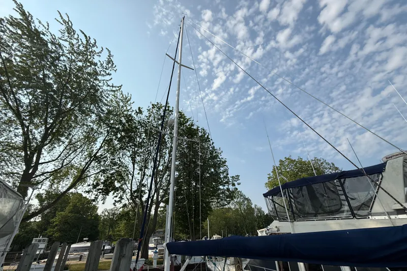 Nino Yacht Photos Pics Sailboat mast of 2007 Tartan 4100 against a clear sky and trees.