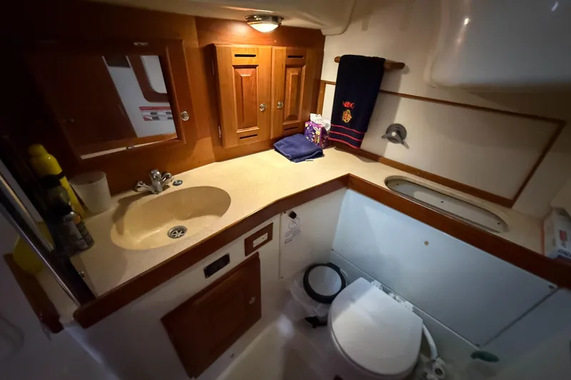 Nino Yacht Photos Pics 2007 Tartan 4100 yacht bathroom with sink, toilet, and wooden cabinetry.