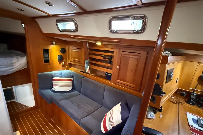 Nino Yacht Photos Pics Cozy interior of 2007 Tartan 4100 sailboat with wooden cabinetry and blue sofa.