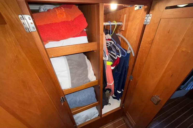 Nino Yacht Photos Pics Wooden closet with shelves and hanging clothes in a 2007 Tartan 4100 yacht.