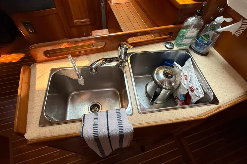 Nino Yacht Photos Pics Kitchen sink area on a 2007 Tartan 4100 yacht with faucet and cleaning supplies.