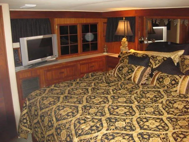  Yacht Photos Pics Luxurious bedroom interior of 1984 Chris-Craft Constellation yacht with elegant bedding and wooden accents.