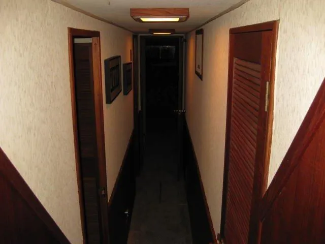  Yacht Photos Pics Narrow hallway inside a 1984 Chris-Craft Constellation boat, featuring wooden doors and paneling.