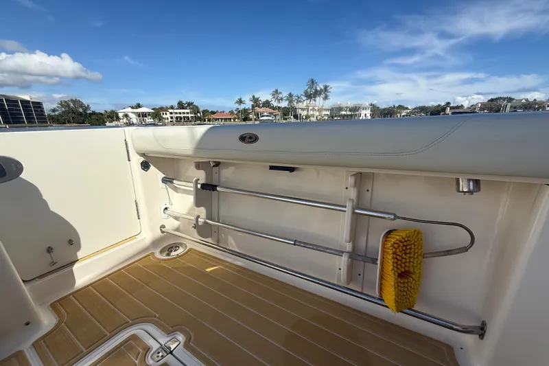  Yacht Photos Pics 2010 Pursuit OS 345 Offshore boat deck with storage and cleaning tools, under clear blue sky.