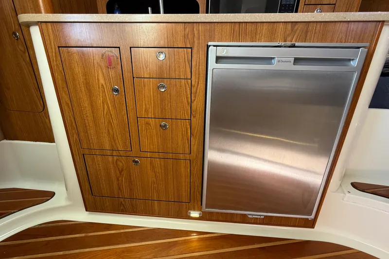  Yacht Photos Pics Wooden cabinetry and stainless steel fridge in 2010 Pursuit OS 345 Offshore boat interior.