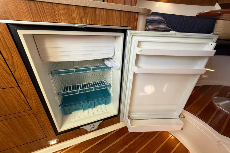  Yacht Photos Pics Open refrigerator inside 2010 Pursuit OS 345 Offshore boat, showcasing wooden interior.