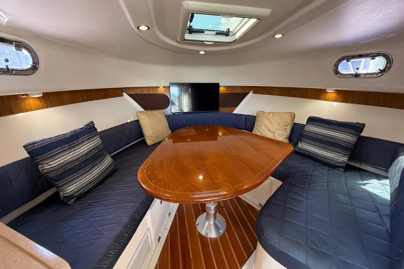  Yacht Photos Pics 2010 Pursuit OS 345 Offshore cabin interior with wood table, blue seating, and striped cushions.