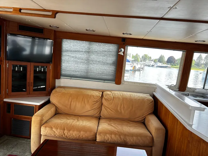 "o My Papa" Yacht Photos Pics Interior of 2003 Nordic Tug 52 with beige sofa, TV, and marina view.