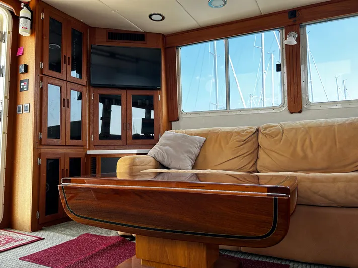 "o My Papa" Yacht Photos Pics Interior of 2003 Nordic Tug 52 with beige sofa, wooden table, and mounted TV.
