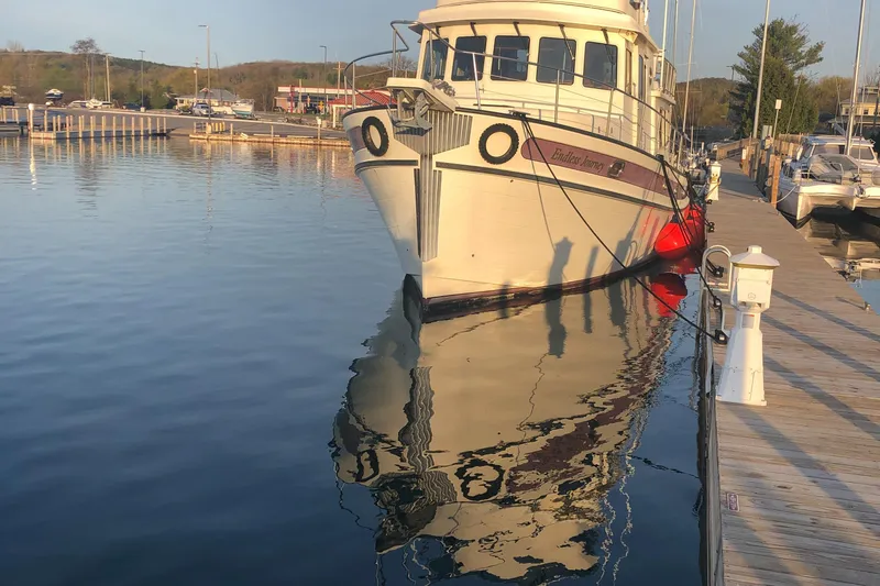 "o My Papa" Yacht Photos Pics 2003 Nordic Tug 52 docked at a marina, reflecting on calm water.