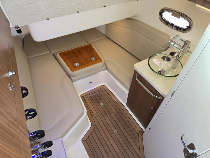  Yacht Photos Pics 2019 Boston Whaler 380 Outrage cabin interior with seating, sink, and wooden flooring.