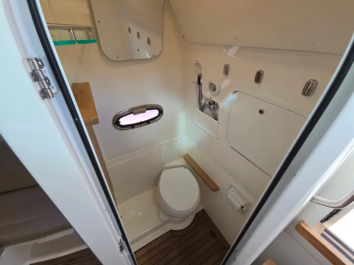  Yacht Photos Pics 2019 Boston Whaler 380 Outrage boat bathroom with toilet, mirror, and wooden accents.