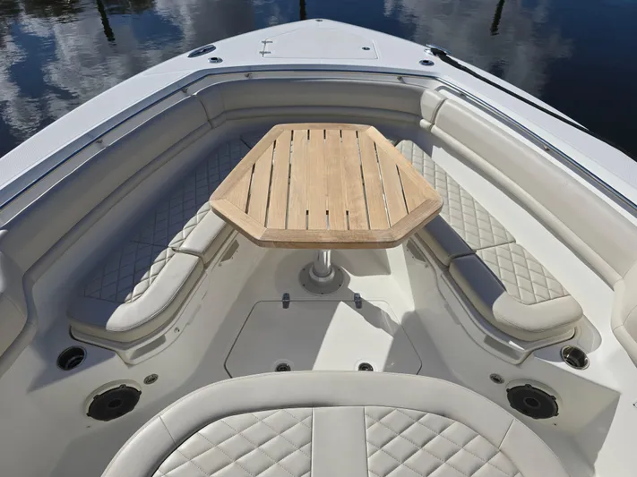  Yacht Photos Pics 2019 Boston Whaler 380 Outrage boat interior with cushioned seating and wooden table.