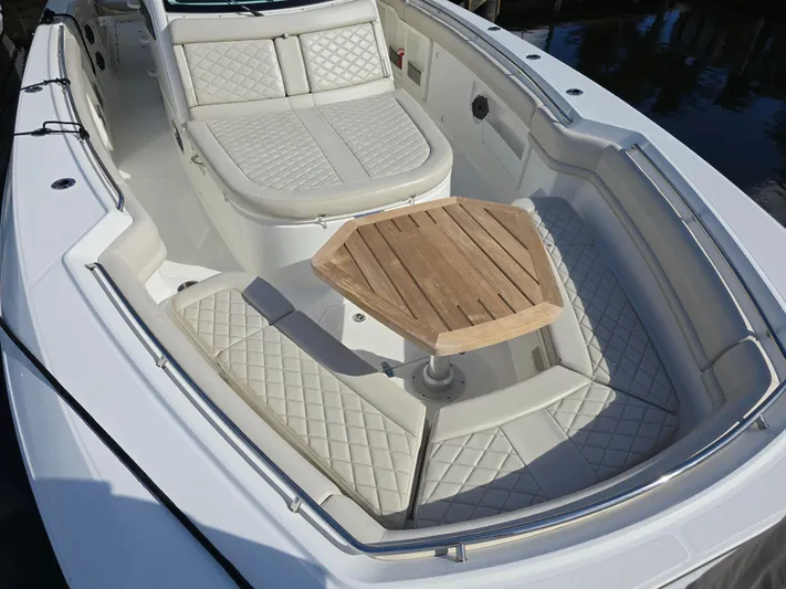  Yacht Photos Pics 2019 Boston Whaler 380 Outrage boat with cushioned seating and wooden table.