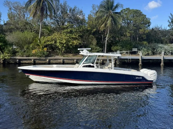  Yacht Photos Pics 2019 Boston Whaler 380 Outrage boat on a calm river, surrounded by lush greenery.