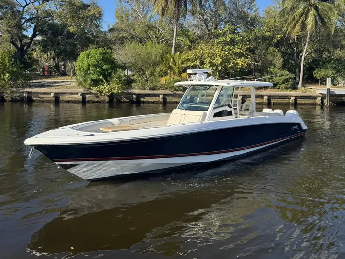  Yacht Photos Pics 2019 Boston Whaler 380 Outrage boat on a calm river, surrounded by lush greenery.
