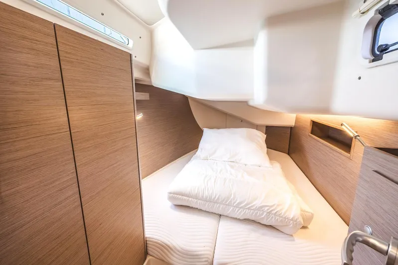  Yacht Photos Pics 2022 Hanse 458 yacht interior cabin with cozy bedding and wooden paneling.