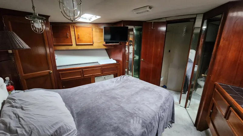 Reel Easy Yacht Photos Pics Luxurious cabin interior of a 1989 Ocean Yachts 55, featuring wood paneling and a cozy bed.