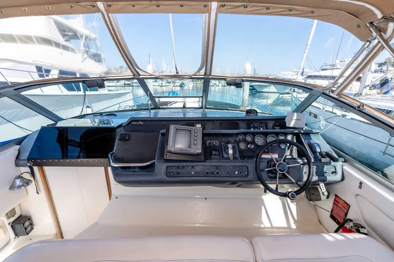 Sea Oddity Yacht Photos Pics 1991 Sea Ray 330 Sundancer helm with navigation equipment and steering wheel in marina setting.