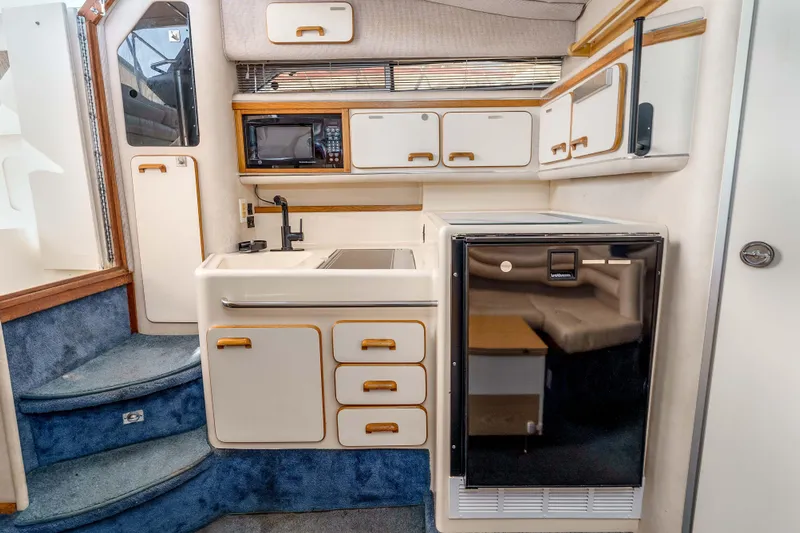 Sea Oddity Yacht Photos Pics 1991 Sea Ray 330 Sundancer interior kitchen with cabinets, microwave, and fridge.