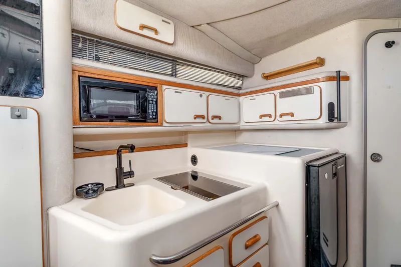Sea Oddity Yacht Photos Pics Interior of 1991 Sea Ray 330 Sundancer boat kitchen with sink, microwave, and cabinets.