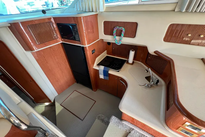 Get Nuts Yacht Photos Pics Interior of 2000 Sea Ray 400 Sedan Bridge yacht, featuring kitchen area with wood cabinetry.