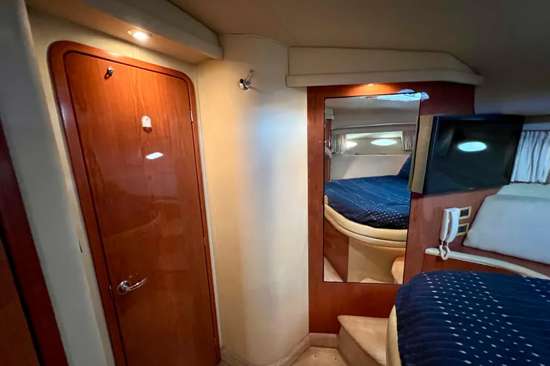 Get Nuts Yacht Photos Pics Interior of 2000 Sea Ray 400 Sedan Bridge, featuring cozy cabin with wood accents and blue bedding.