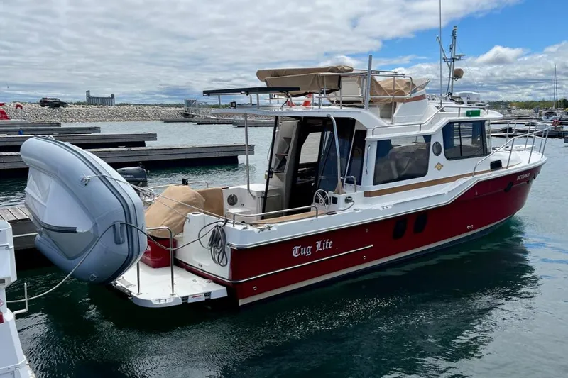 Tug Life Yacht Photos Pics 2017 Ranger Tugs R-29 CB boat docked, featuring a red hull and inflatable dinghy.