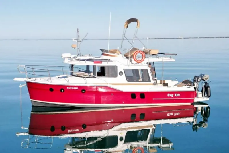 Tug Life Yacht Photos Pics 2017 Ranger Tugs R-29 CB boat on calm water, reflecting its vibrant red hull.