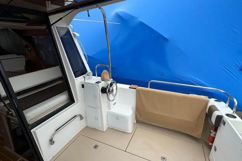 Tug Life Yacht Photos Pics 2017 Ranger Tugs R-29 CB boat cockpit with steering wheel and seating, blue cover background.