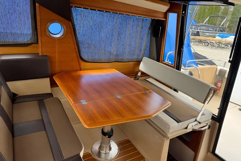 Tug Life Yacht Photos Pics Interior of 2017 Ranger Tugs R-29 CB with wooden table and seating area.