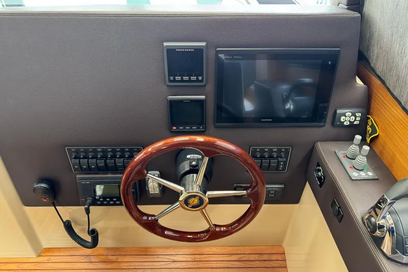 Tug Life Yacht Photos Pics 2017 Ranger Tugs R-29 CB helm with wooden steering wheel and modern navigation controls.