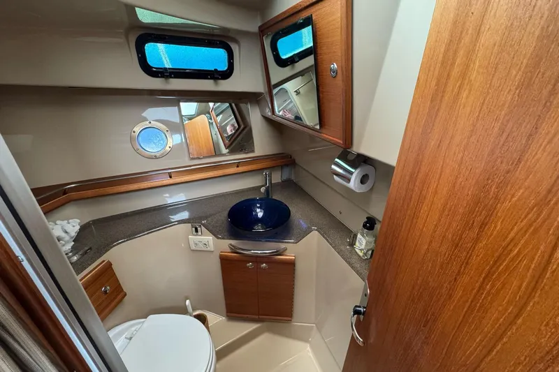 Tug Life Yacht Photos Pics 2017 Ranger Tugs R-29 CB bathroom with wood accents, blue sink, and porthole window.