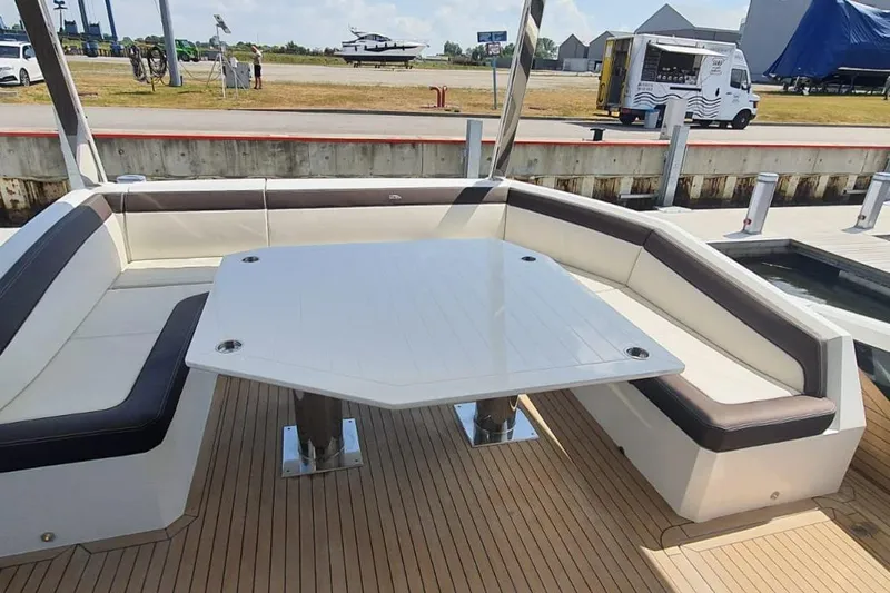  Yacht Photos Pics Luxurious seating area on 2023 Galeon 640 Fly yacht with sleek table and cushioned benches.
