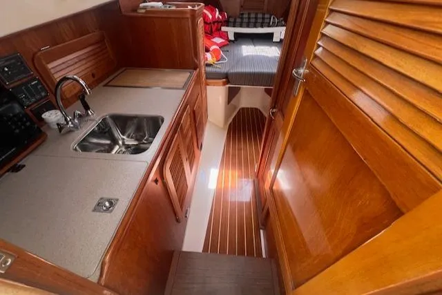 Free Will Yacht Photos Pics 2003 Hinckley Extended Hardtop Pilothouse 36 interior with wooden cabinetry and compact kitchen.