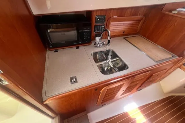 Free Will Yacht Photos Pics 2003 Hinckley Pilothouse 36 boat kitchen with sink, microwave, and wooden cabinetry.
