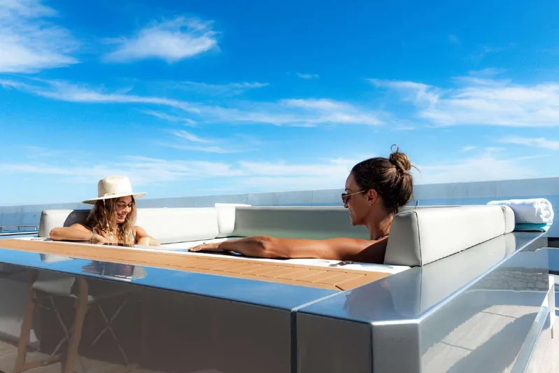 Clarity Yacht Photos Pics Two people relaxing on a 2022 Riva 90' Argo yacht under a clear blue sky.