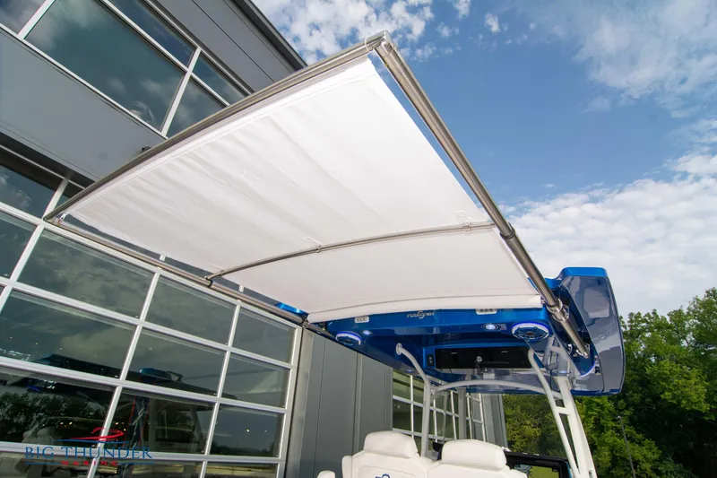  Yacht Photos Pics 2023 Fountain 34 CC boat with extended canopy, near modern building.