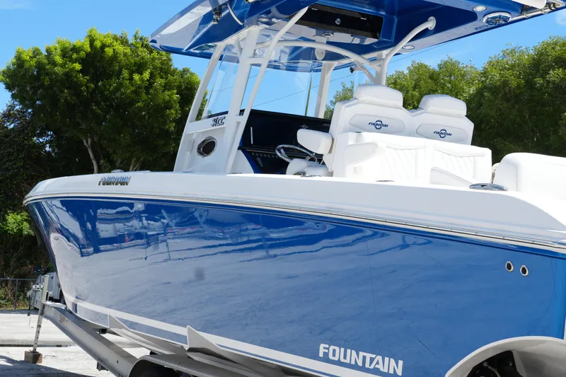  Yacht Photos Pics 2023 Fountain 34 Center Console boat with sleek blue and white design, docked outdoors.
