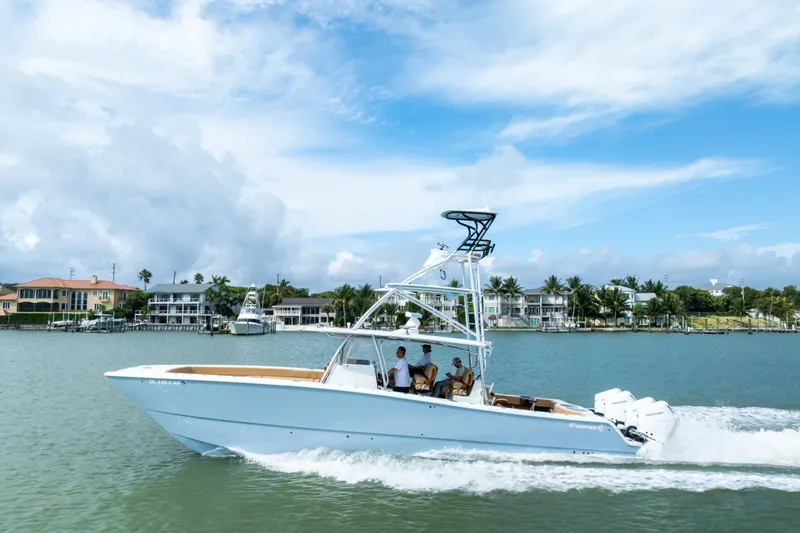  Yacht Photos Pics 2025 Freeman LR boat cruising on a scenic waterfront with luxury homes in the background.