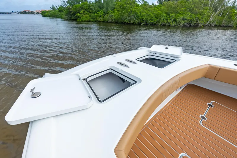  Yacht Photos Pics 2025 Freeman LR boat deck with open storage compartments, near lush shoreline.