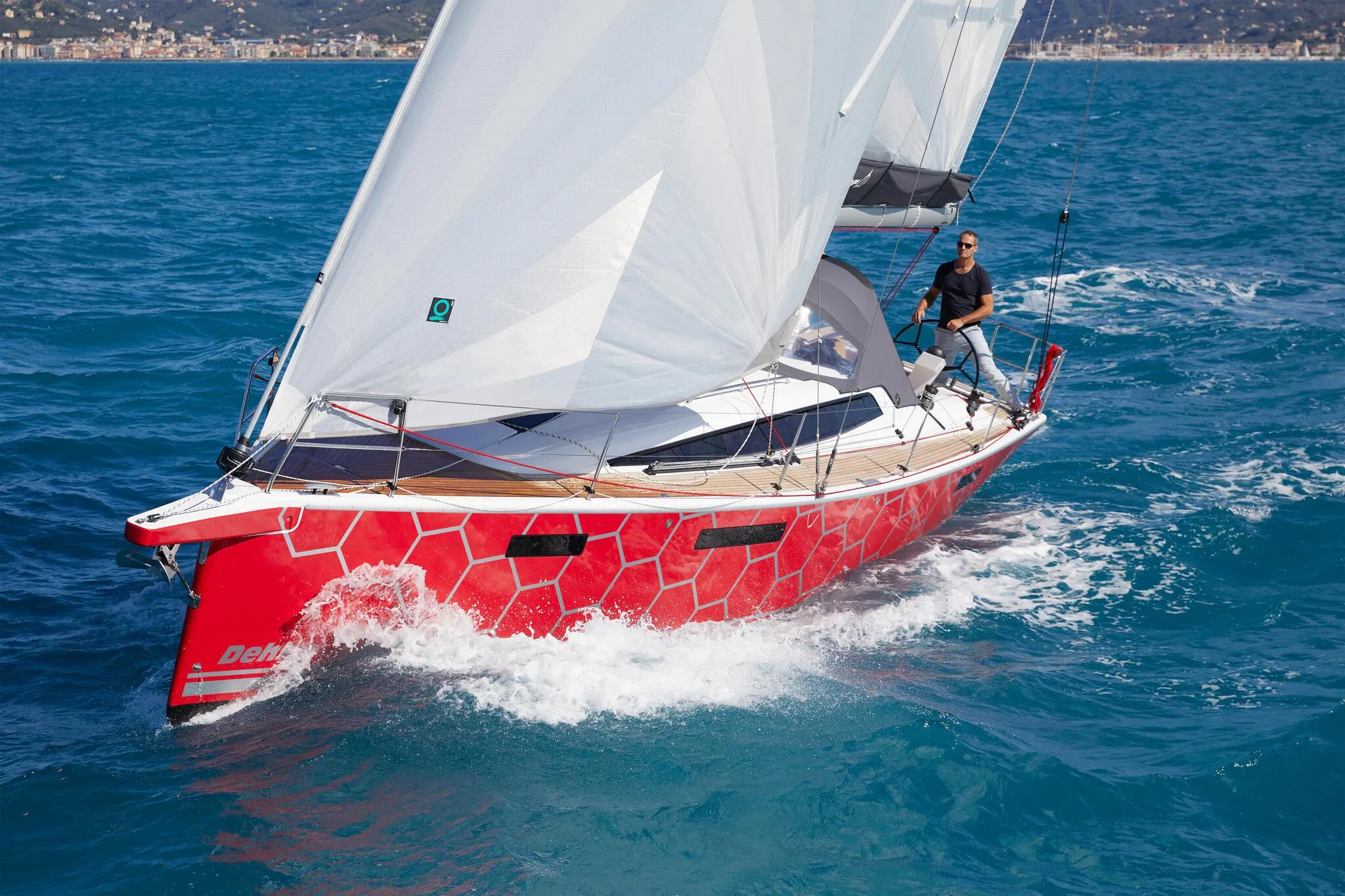 2025 Dehler 38 SQ sailboat with red hull sailing on blue ocean.