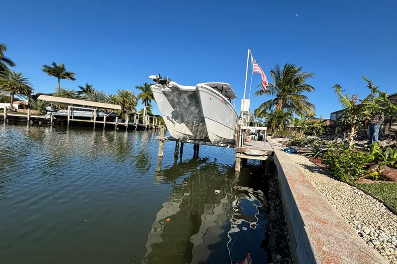  Yacht Photos Pics 2023 World Cat 295 CC boat docked by a waterfront with palm trees and American flag.