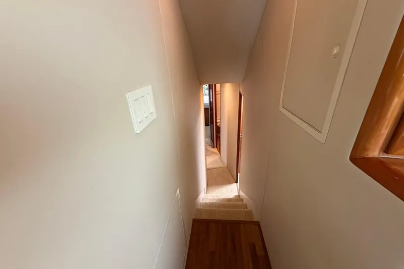 Breakaway Yacht Photos Pics Narrow hallway inside 2004 Viking 56 Convertible yacht, featuring wooden accents and carpeted stairs.