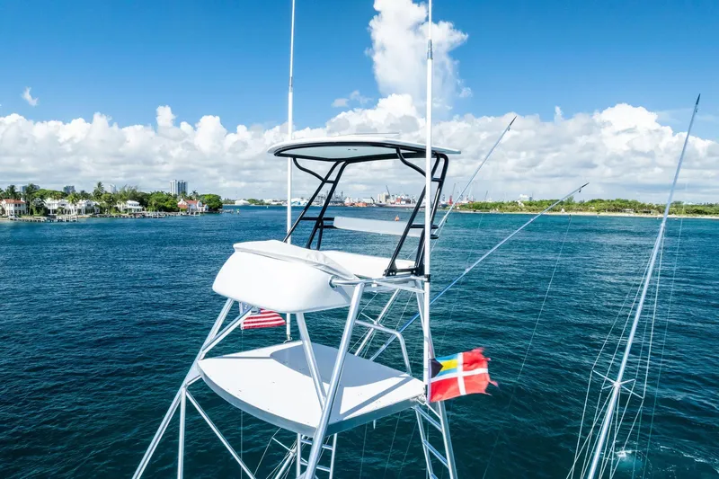 Nic-nac Yacht Photos Pics 1977 Merritt Sportfish boat with flags, cruising on a sunny day near coastal homes.