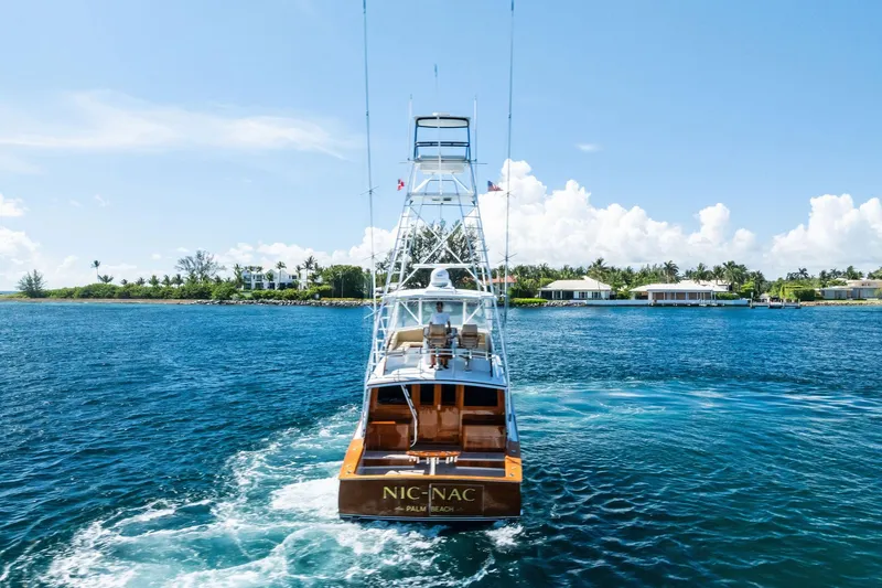 Nic-nac Yacht Photos Pics 1977 Merritt Sportfish yacht cruising on blue waters near a tropical shoreline.