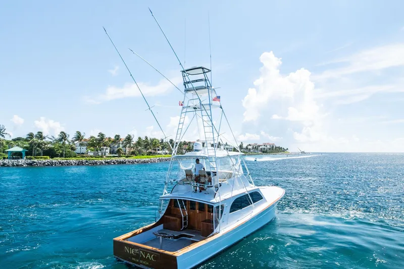Nic-nac Yacht Photos Pics 1977 Merritt Sportfish yacht cruising near a scenic coastline under a clear blue sky.