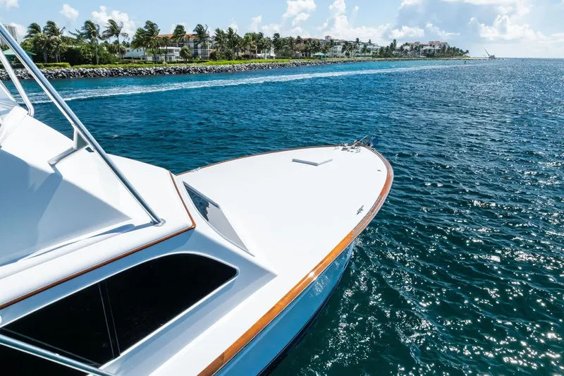 Nic-nac Yacht Photos Pics 1977 Merritt Sportfish yacht cruising near a scenic coastline under a clear blue sky.